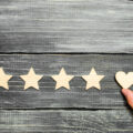 The hand puts the heart to the four stars. Choice of buyers. Universal recognition and admiration. Rating of a hotel or restaurant, product or mobile application. Increase in rating and prestige