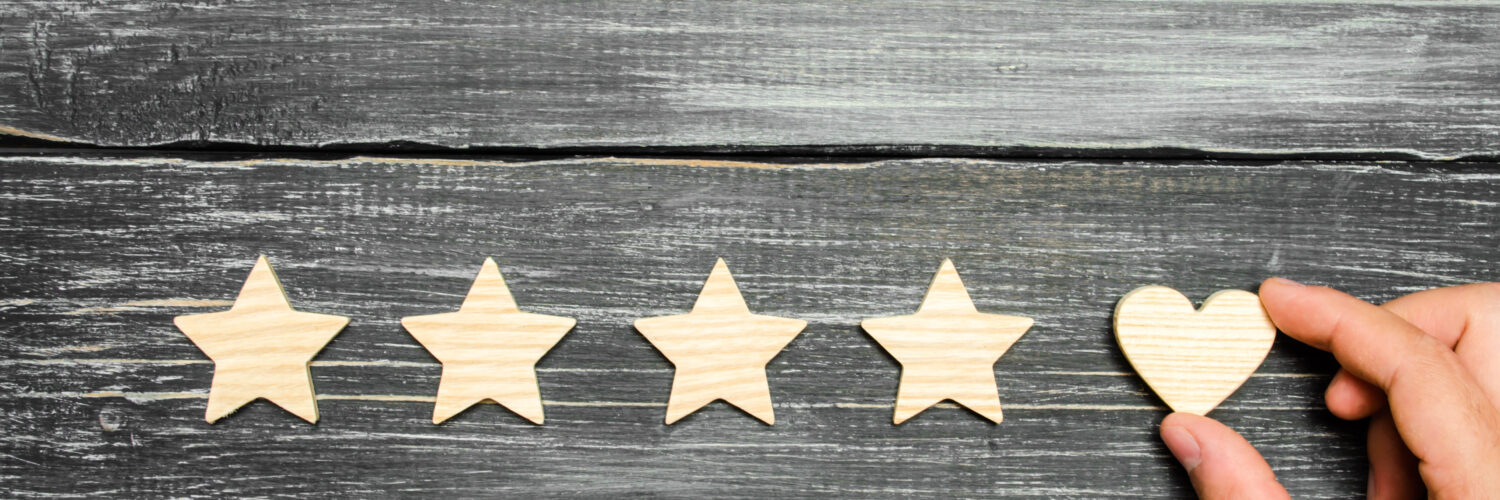 The hand puts the heart to the four stars. Choice of buyers. Universal recognition and admiration. Rating of a hotel or restaurant, product or mobile application. Increase in rating and prestige